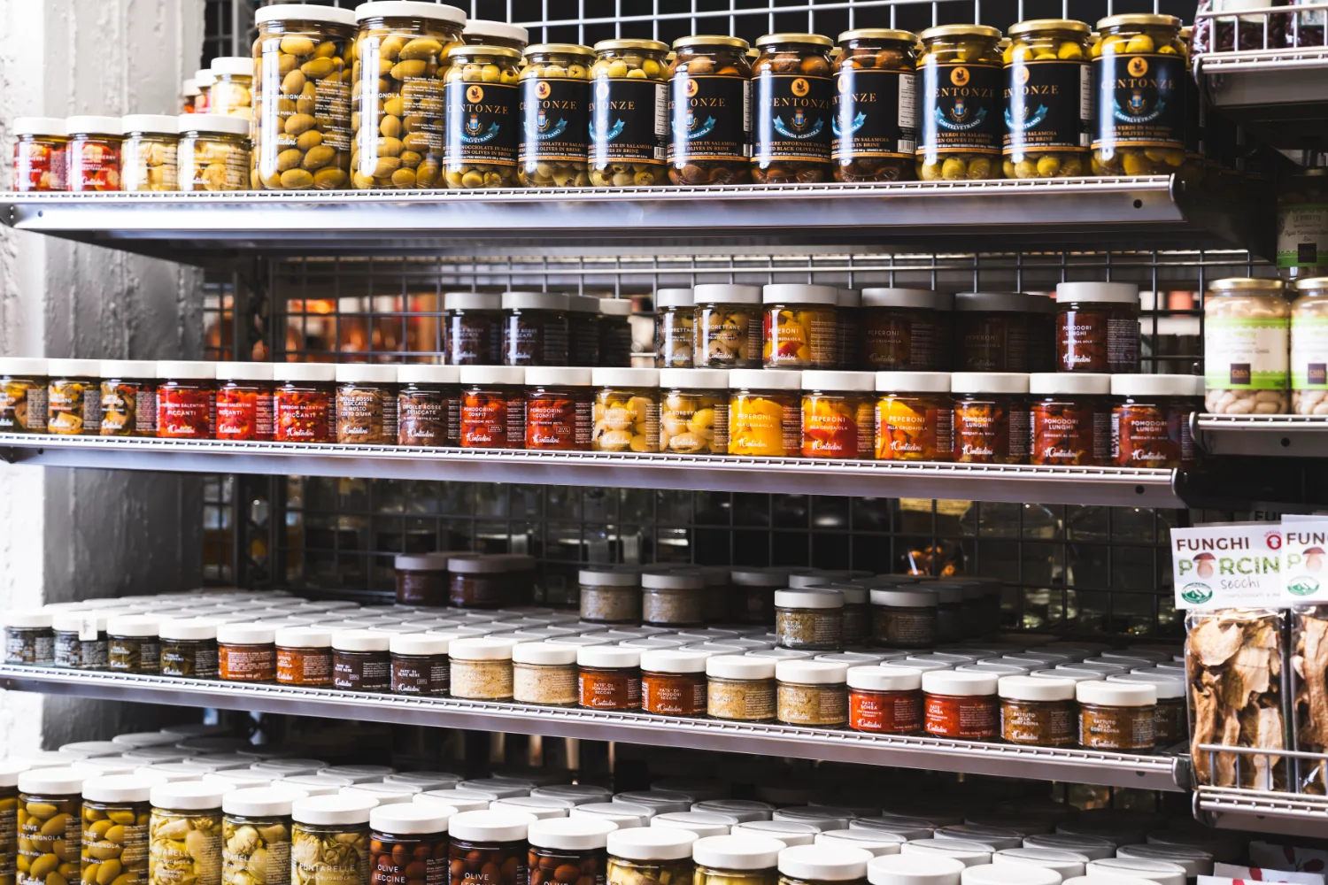 Das Bild zeigt ein Regal mit einer großen Auswahl an eingelegten Produkten.