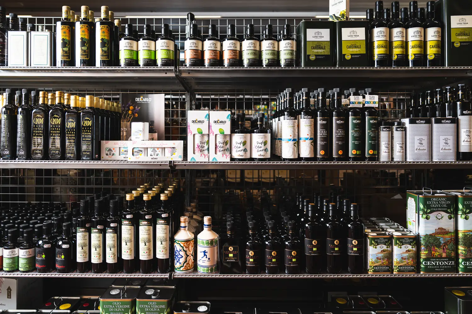 Auf dem Bild sieht man ein Regal mit einer großen Auswahl an verschiedenen Olivenölen.