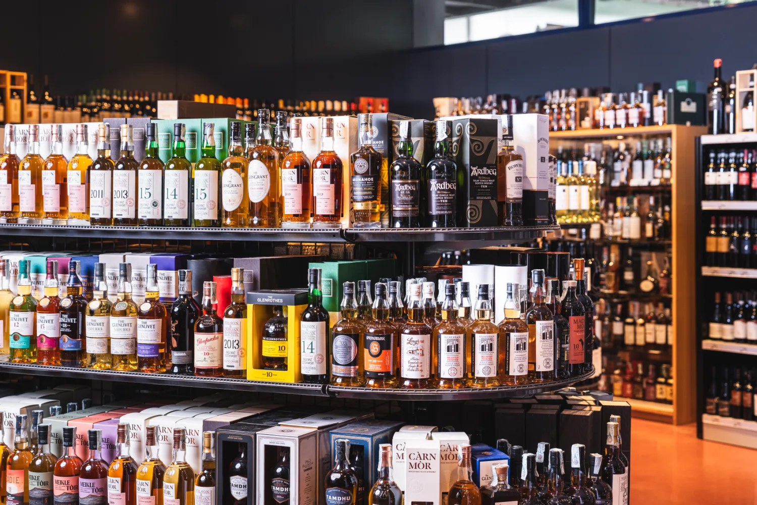 Das Bild zeigt ein Regal mit Spirituosen, dahinter ist ein weiteres Regal mit Spirituosen zu sehen.